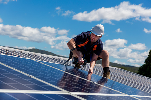 Solar panel installer with drill installing solar panels
